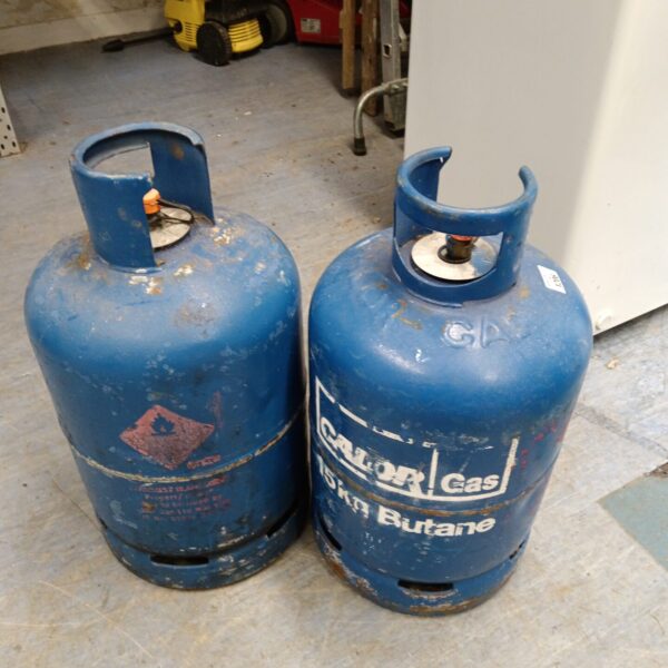 Two blue Calor Gas bottles, one full and one empty, for outdoor use.