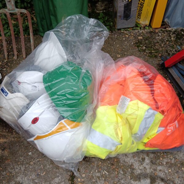 Sack of high visibility vests and hard hats for workwear.