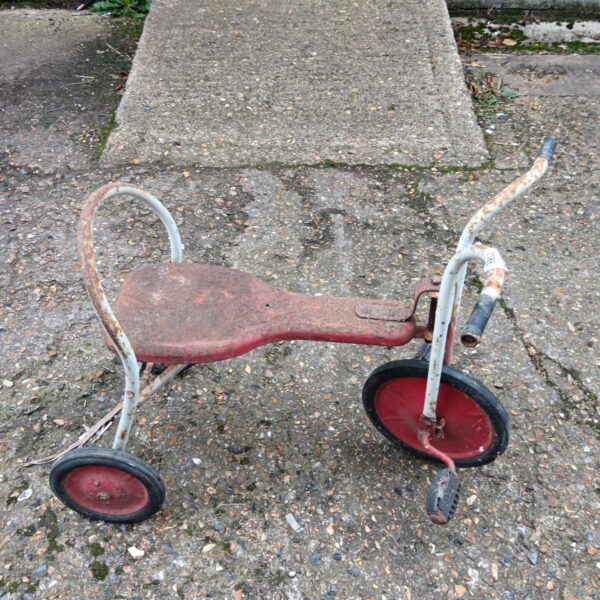 Red vintage Triang child's trike with white handlebars.