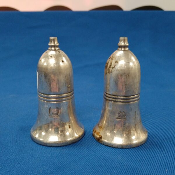 Antique silver plate salt and pepper pots on a blue surface.