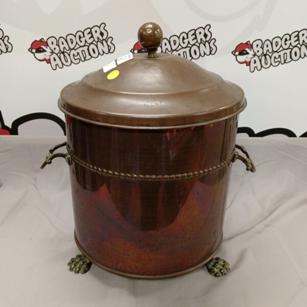 Vintage copper log bin with ornate claw feet for fireside storage.