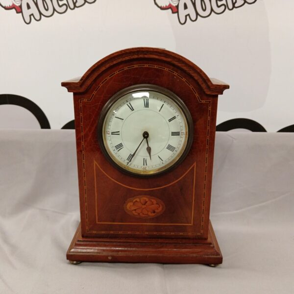 Antique French mantle clock with inlaid wooden case and Roman numeral face.