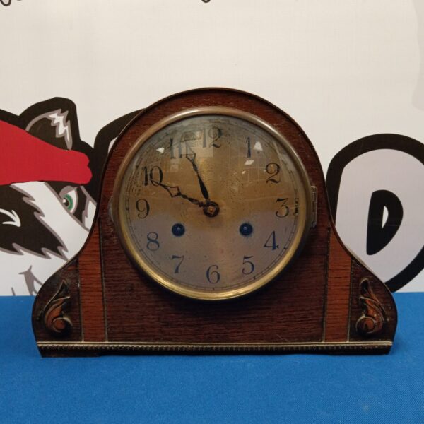 Front view of antique wooden mantle clock with Roman numerals.