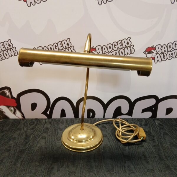 Vintage brass bankers lamp with green glass shade on desk.