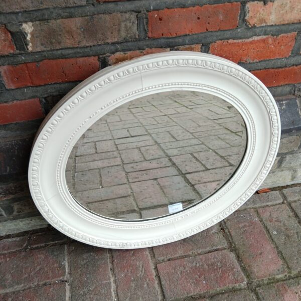 Antique oval mirror with white frame, vintage wall decor.