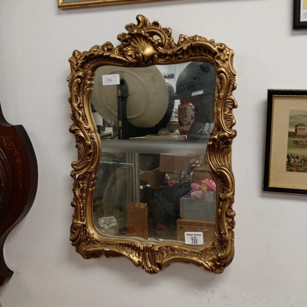 Ornate gilt framed French mirror with detailed carving.