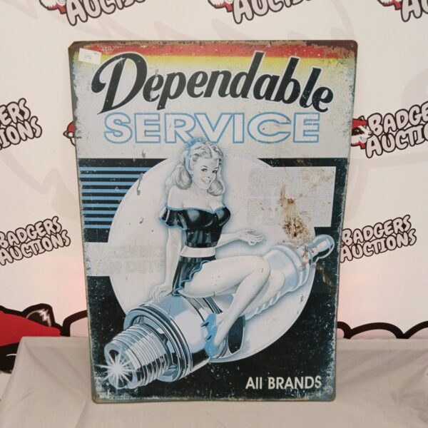 Vintage spark plug tin sign with pin-up girl illustration.