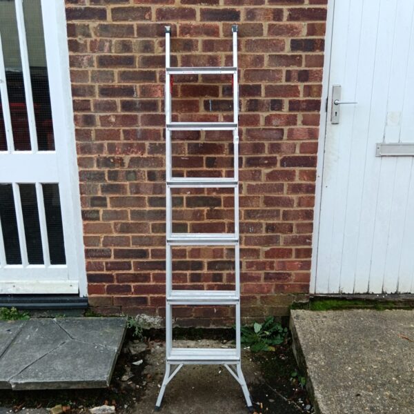 Silver aluminium 3-way ladder leaning against a white wall.