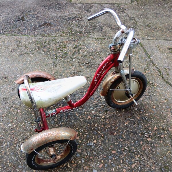 Red vintage Schwinn trike needing restoration.