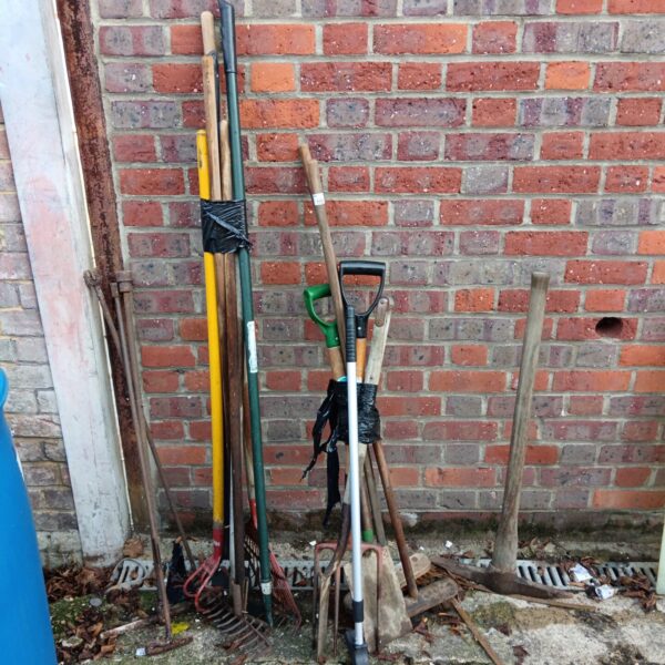 Vintage garden tool lot with rakes and a pickaxe.