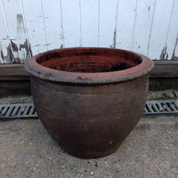 Large terracotta planter with weathered patina for garden display.