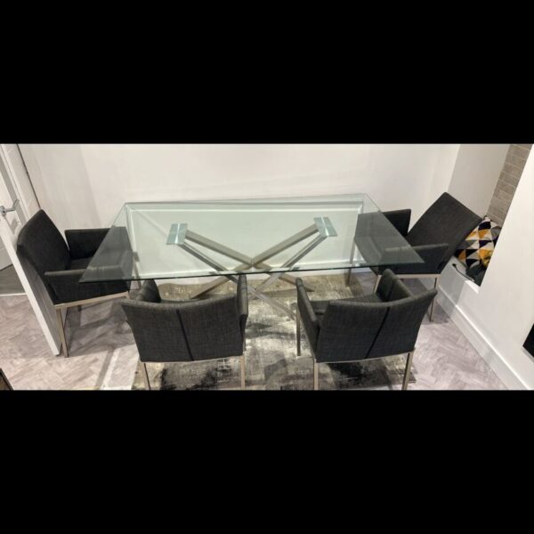 Modern glass dining table with four chrome chairs in a dining room.
