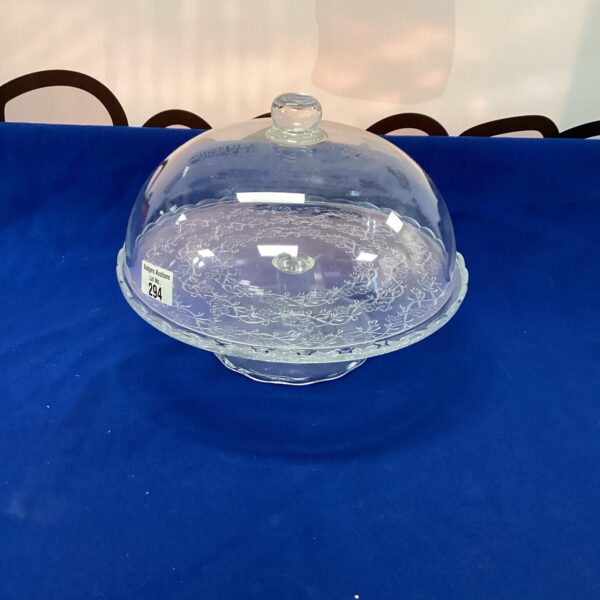 Vintage glass cake cloche with embossed pattern on display.