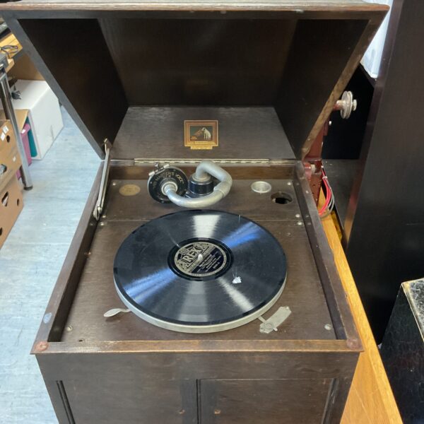 Side view of a vintage HMV gramophone with wooden cabinet.