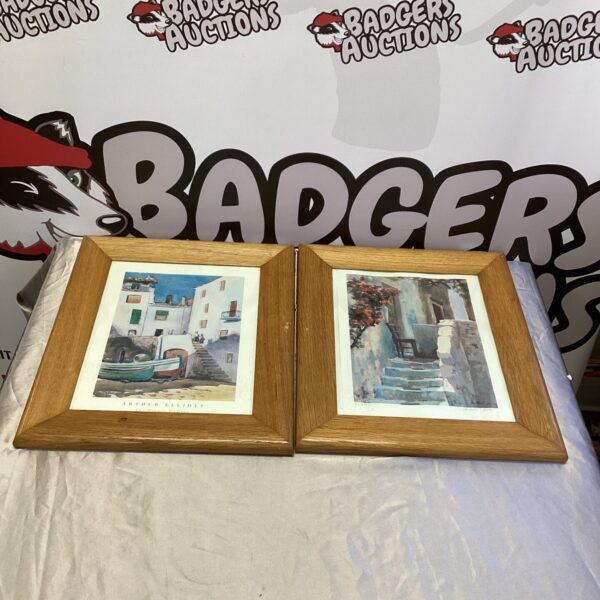 Two framed signed village prints depicting idyllic scenes.