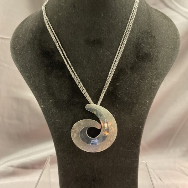 Close-up of a silver swirl pendant necklace with a double chain.