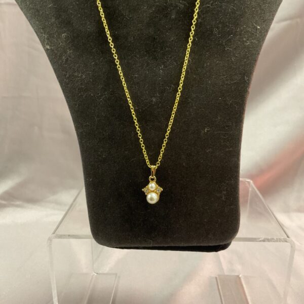 Delicate gilt pearl locket necklace on silver chain.