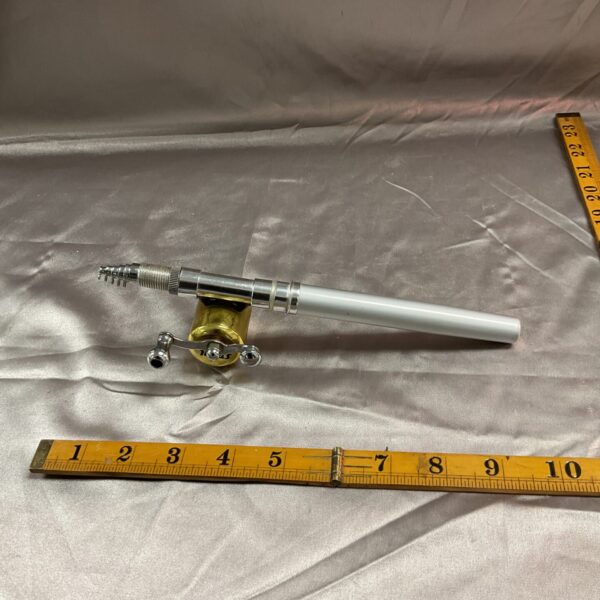 Miniature fishing rod and reel on a white surface.