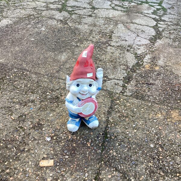 Colourful plastic garden gnome with pickaxe in a garden setting.