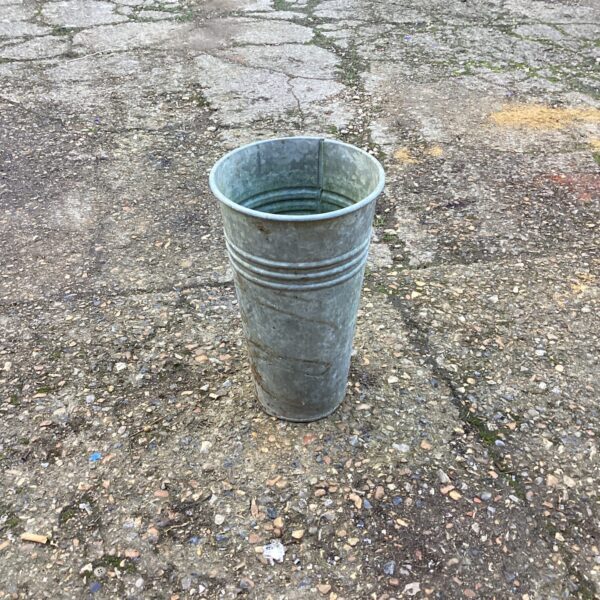 Vintage galvanised flower bucket in a garden setting.