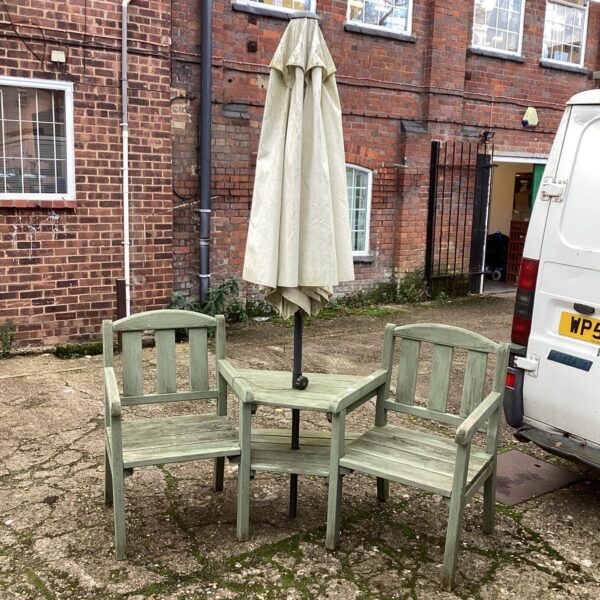 Vintage wooden garden seats with parasol in a garden setting.