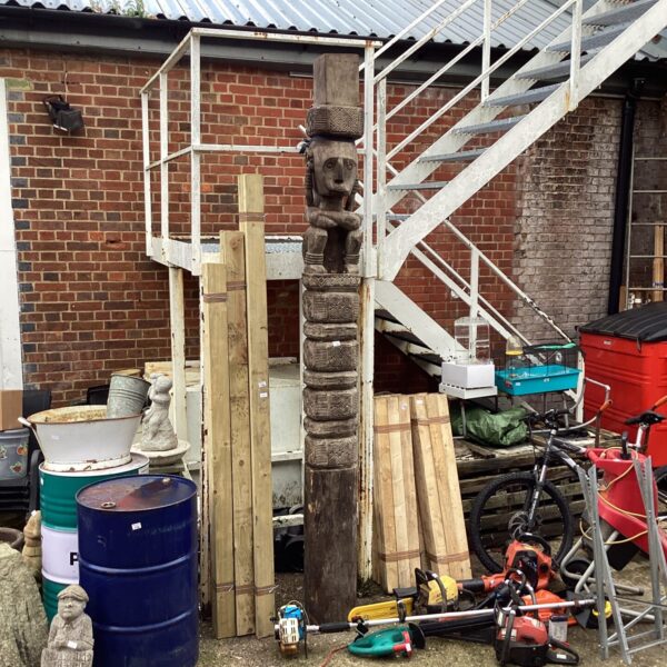Large carved totem pole in a garden setting.