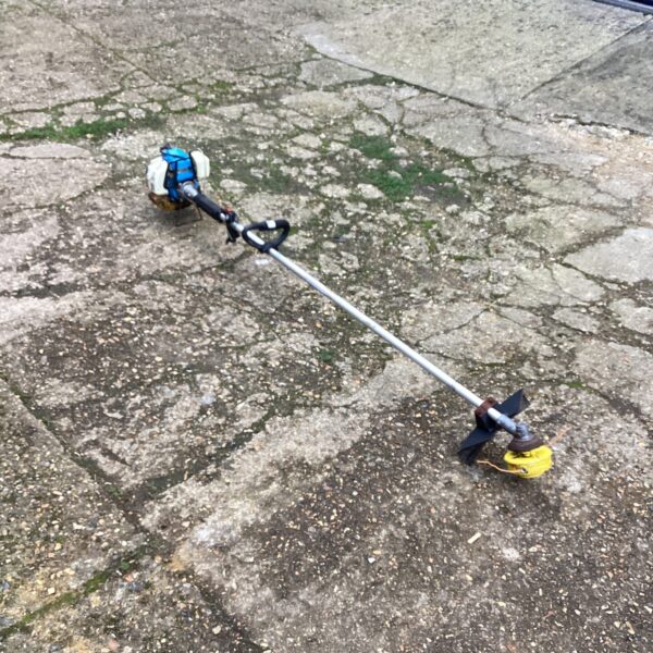 Petrol garden strimmer with a long shaft and cutting head.