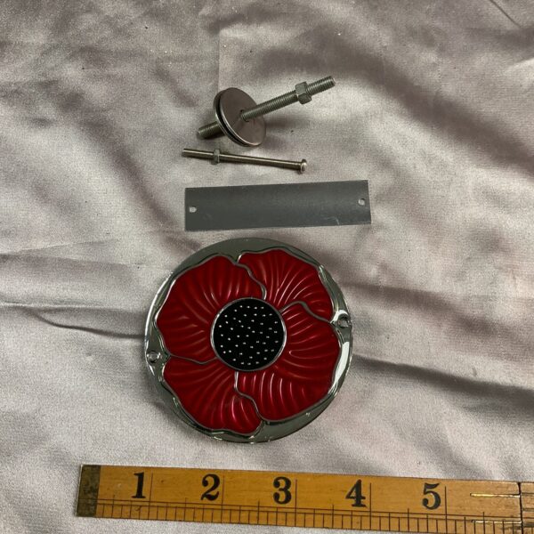 Vintage red poppy car badge for classic vehicles.