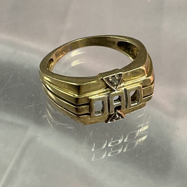 Close-up of a 9ct gold ring with “Dad” engraved on it.