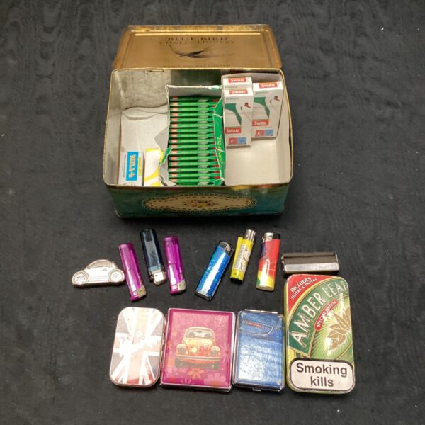 Vintage smoking paraphernalia lot with tin, lighters and rolling machine.