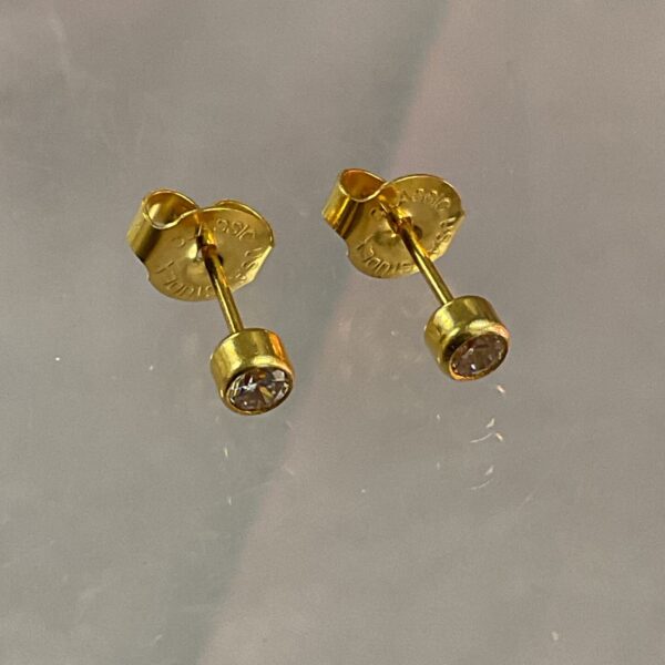 Close-up of 9ct gold stud earrings with a white stone setting.
