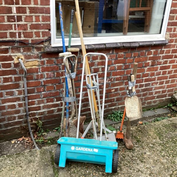 Garden tool lot featuring a blue seed spreader and hand tools.