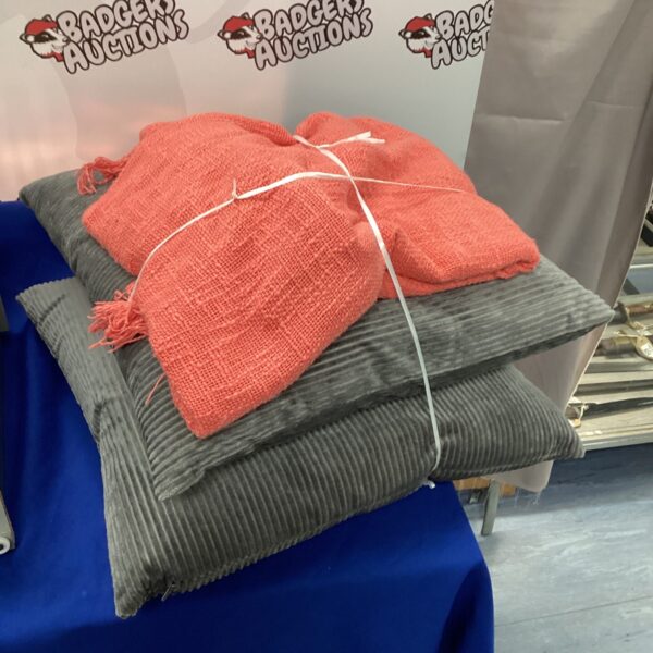 Coral knitted throw and grey cushions set for home decor.