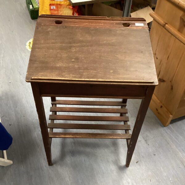 Vintage wooden school desk with sloped writing surface.