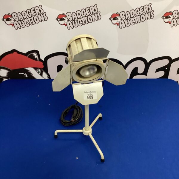 Vintage movie spotlight lamp with adjustable head and weighted base.