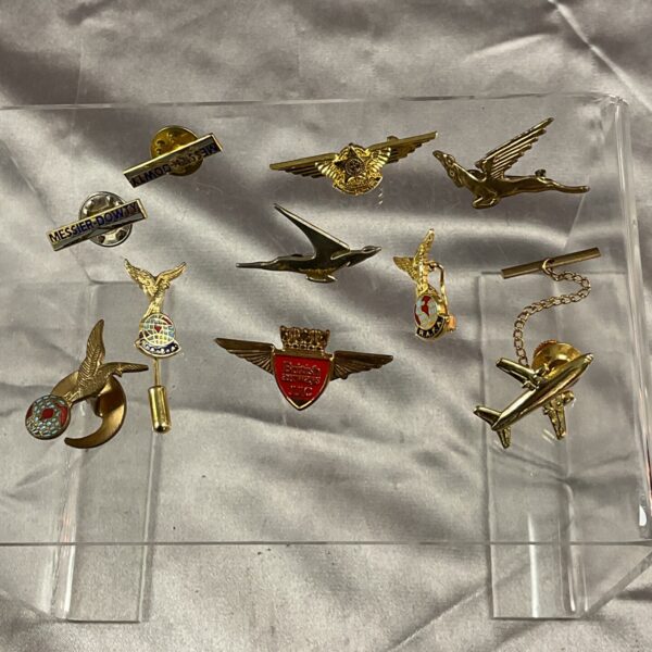 Collection of vintage aviation pin badges and pilot wings.