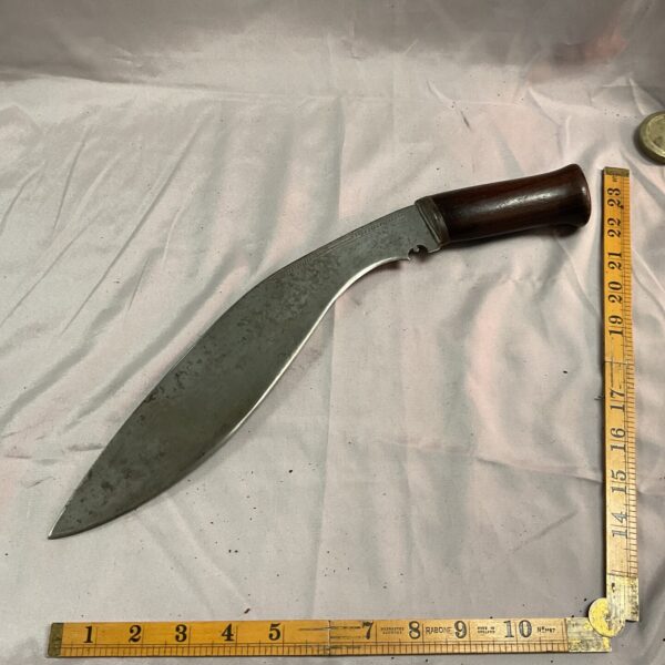 Vintage kukri knife with a curved blade and wooden handle.
