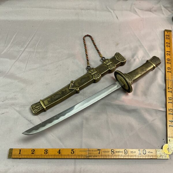Antique Oriental brass sword with curved blade and detailed hilt.
