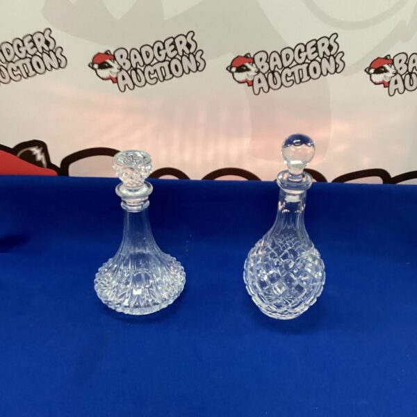 Two vintage crystal decanters on a dark surface.