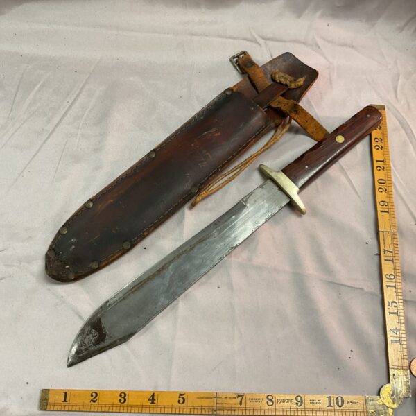 Vintage Bowie knife with leather sheath, antique collectible blade.