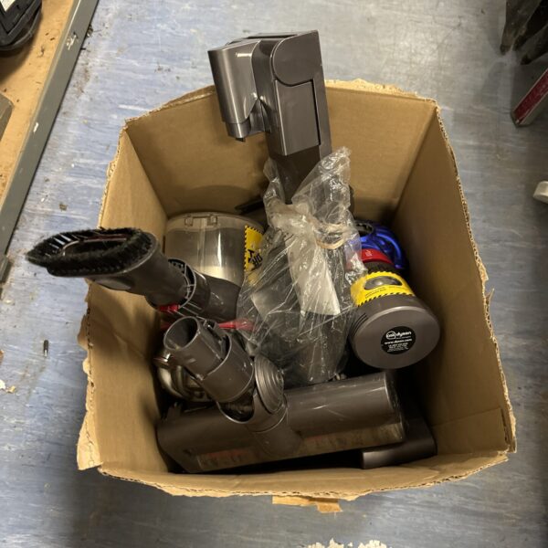 Assorted Dyson vacuum cleaner parts in a cardboard box.