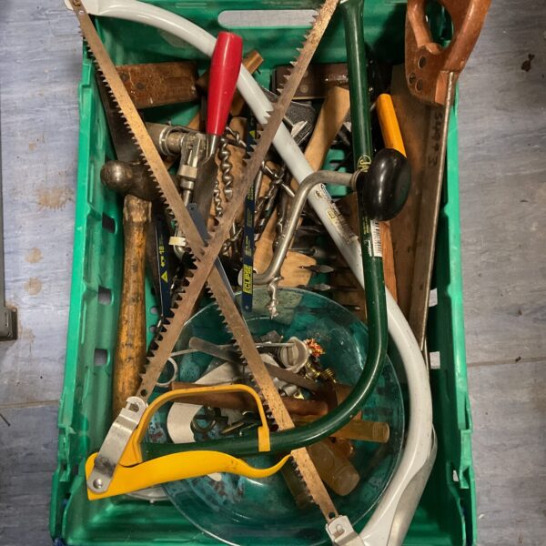 Mixed tool lot in a plastic crate, including saws and hammers.
