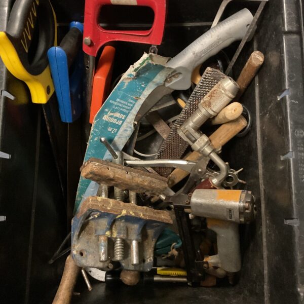 Assorted tools and hardware in a plastic crate for DIY projects.