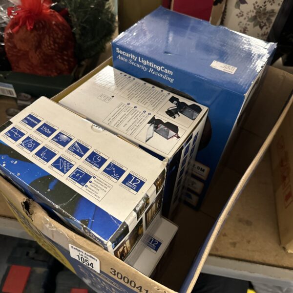 Box of four outdoor security lights with motion sensor technology.
