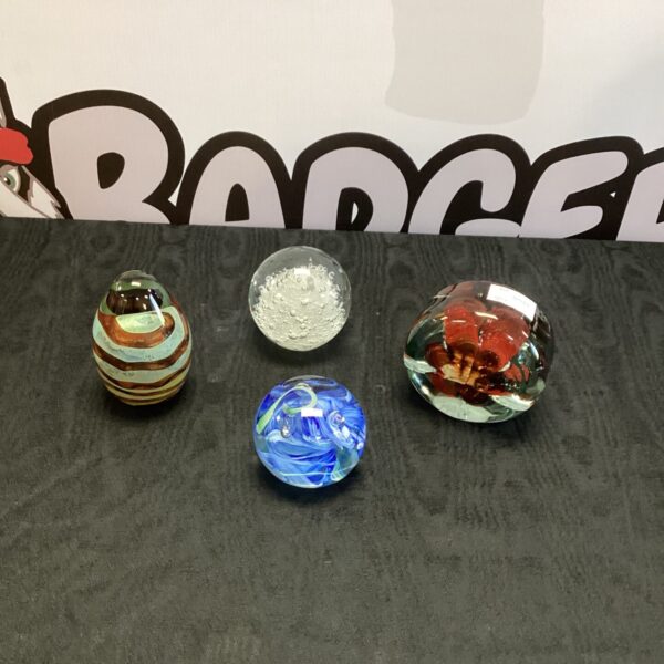 Four colourful glass paperweights displayed together.