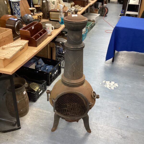 Antique cast iron chiminea with mesh panel in a vintage setting.