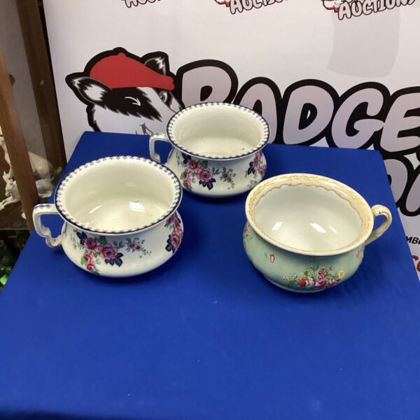 Three antique porcelain chamber pots with floral designs.