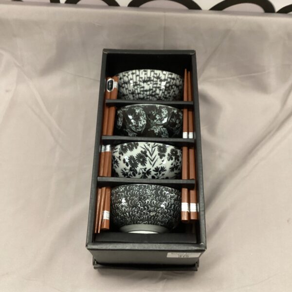 Chinese rice bowl set with wooden chopsticks on a black background.