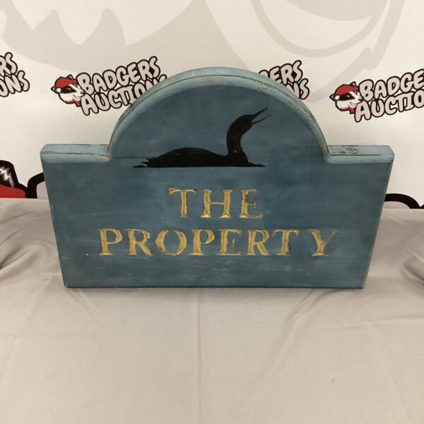 Vintage wooden "The Property" sign with a bird illustration.