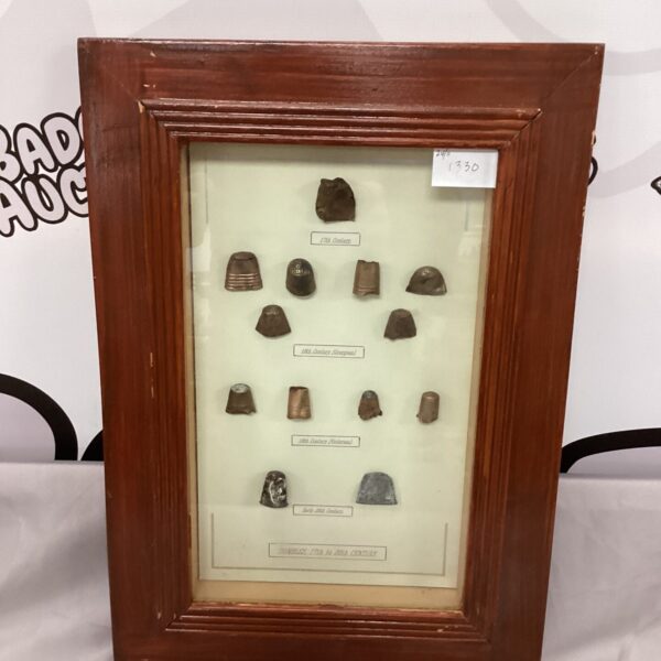 Framed antique thimbles displayed as a collectible sewing tool arrangement.